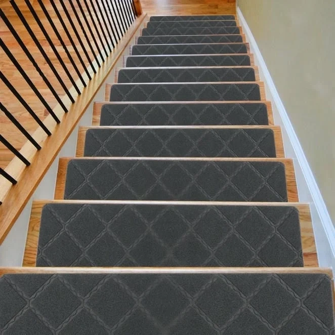 A high-angle view looking down a wooden staircase featuring dark grey, diamond-patterned rectangular stair treads.