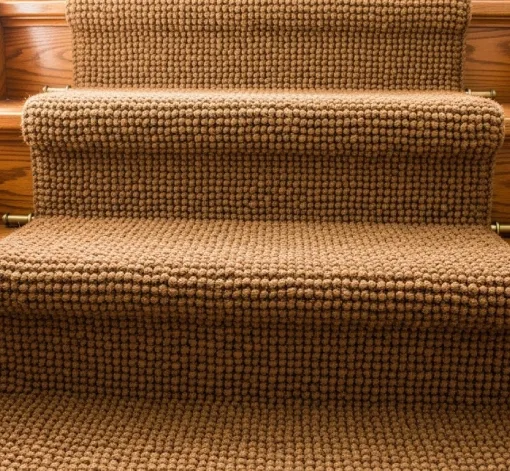 A textured, light brown coir stair runner secured to wooden steps with brass stair rods.