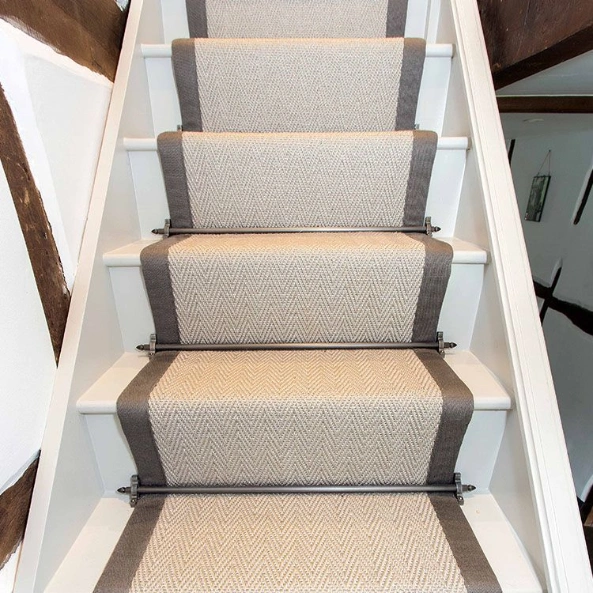 Cream herringbone stair runner with grey border and black stair rods.