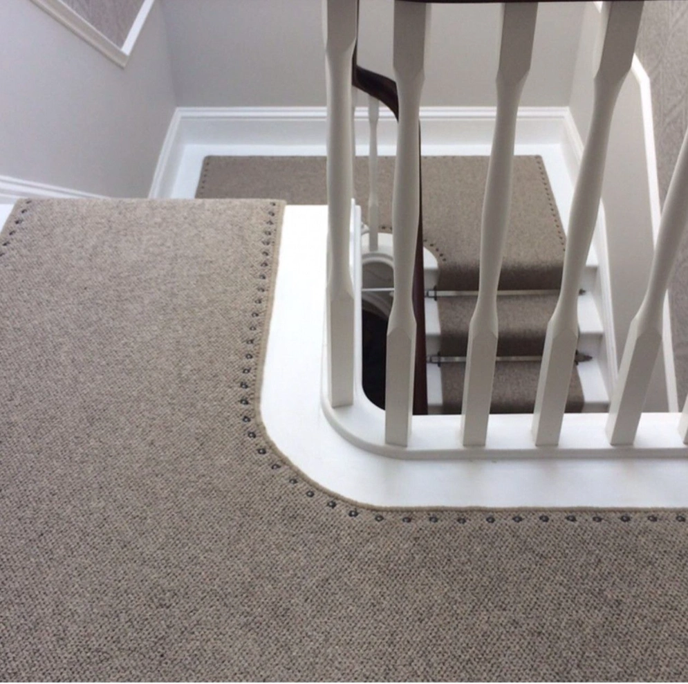 Grey textured landing carpet with decorative metal stud borders.