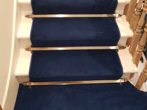 Navy blue velvet stair runner with decorative gold stair rods.