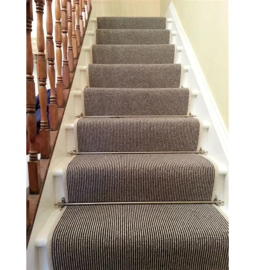 Safed seedhiyon per lagaya gaya barik dhariyon wala (thin stripes) carpet runner jisay brass ki rods se tight kiya gaya hai.