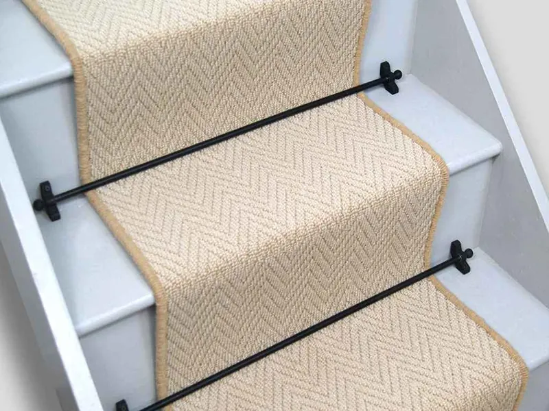 chevron stair runner secured with black metal stair rods on white stairs.