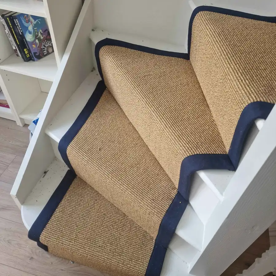 close-up view of white wooden winding stairs fitted with a natural tan stair sisal carpet runner