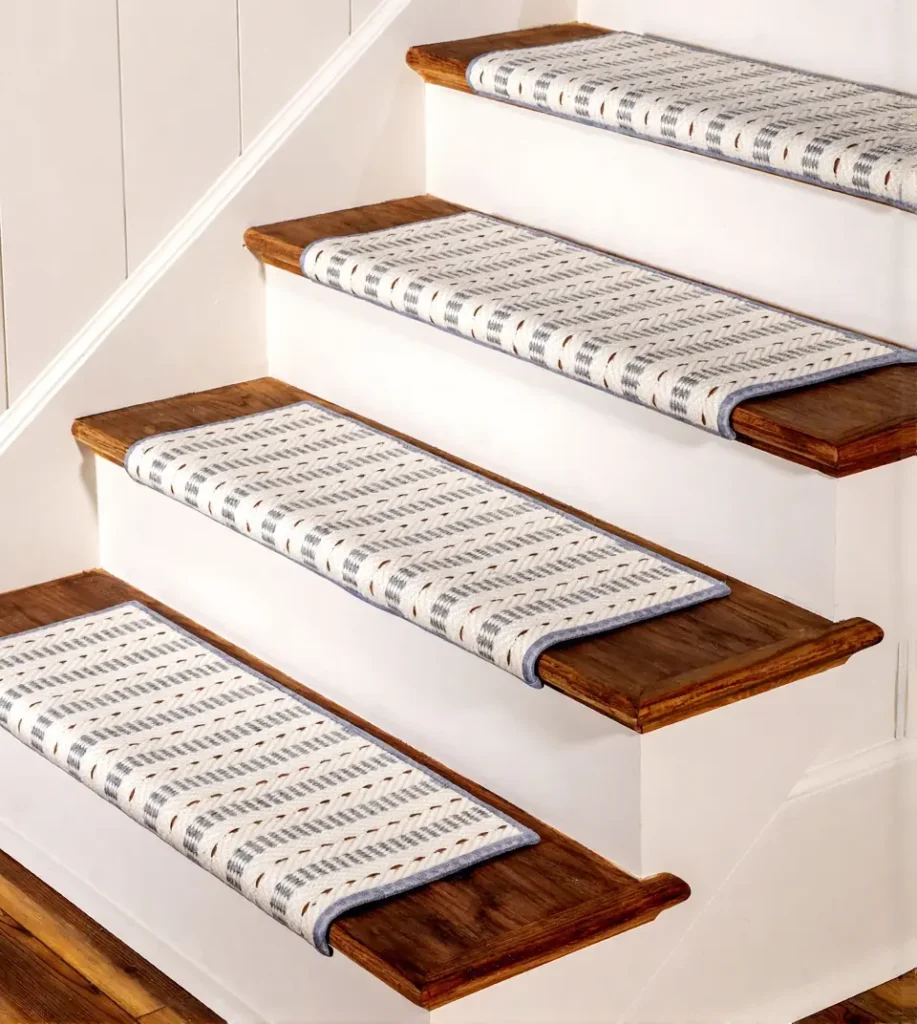 cream and grey stair tread carpets with blue borders installed on dark wood steps with white risers.