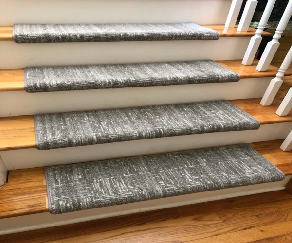 grey textured carpet treads with a bullnose edge that wraps over the front of each step.