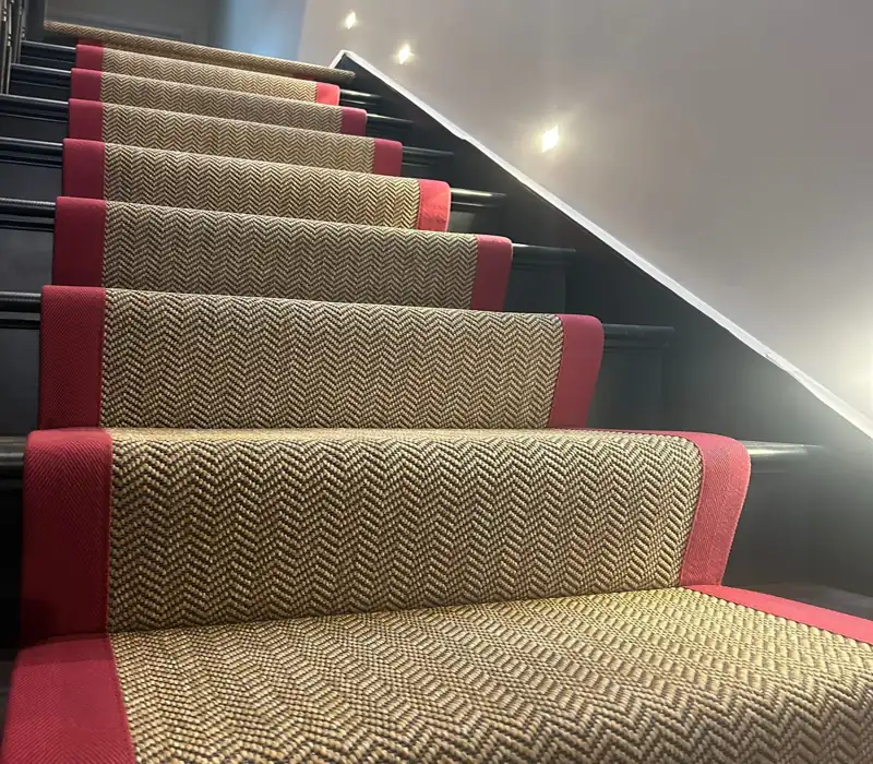 herringbone-patterned sisal stair runner with a bold red fabric border.