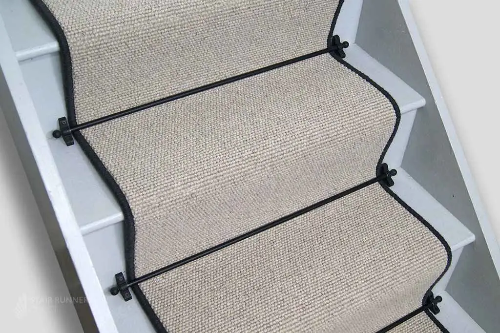 high-angle view of a creamy beige wool sisal stair runner installed on white wooden stairs.