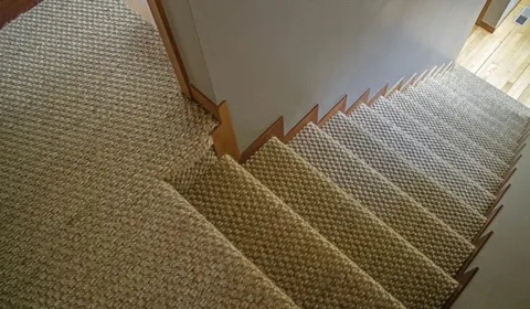 Light cream synthetic wall-to-wall stair carpet close-up with natural imperfections