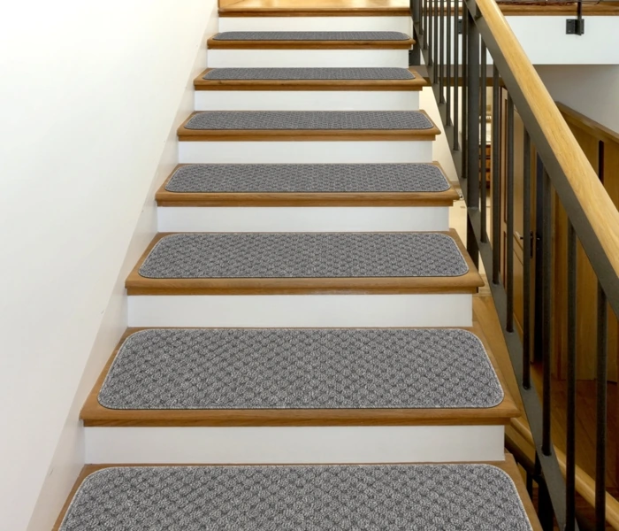 patterned non-slip carpet treads installed on a wooden staircase with white risers and a black metal railing.