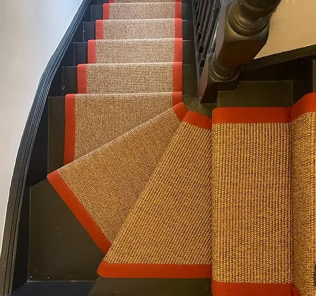 staircase featuring black painted wood steps fitted with high-quality sisal carpet runners.