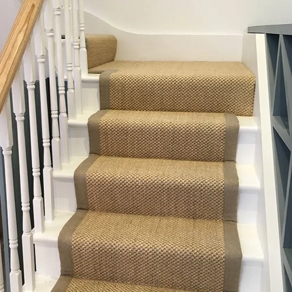 staircase with a sisal carpet runner featuring a wide grey fabric border.