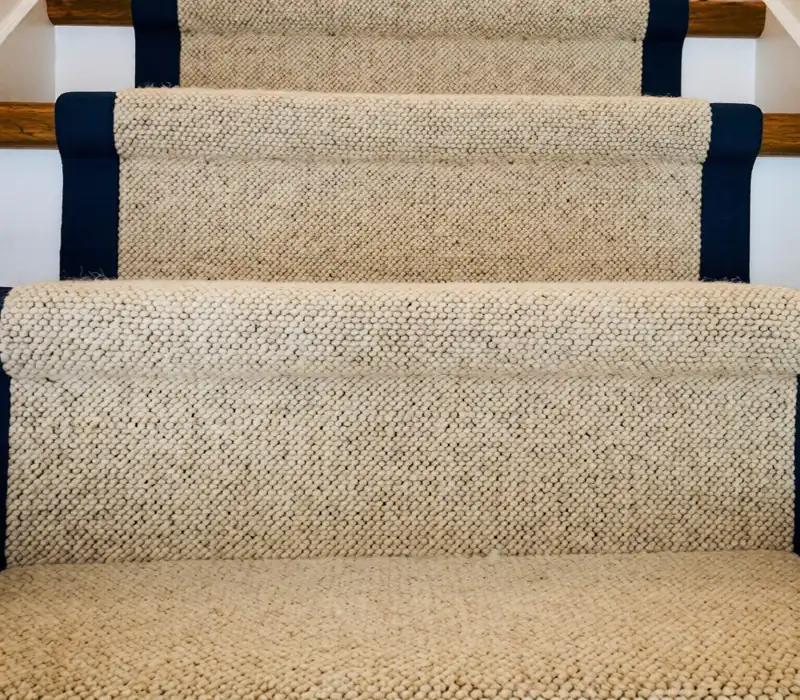 staircase with white balusters and wooden treads, featuring a herringbone-patterned beige sisal stair runner