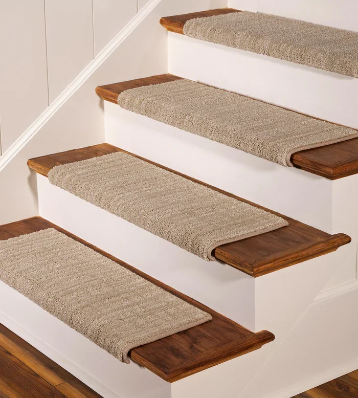 synthetic carpet stair treads with a subtle ribbed texture, installed on dark wood stairs with white risers.