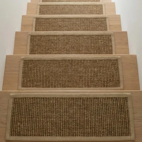 woven sisal stair treads with a beige fabric border, centered on light-toned wooden steps.