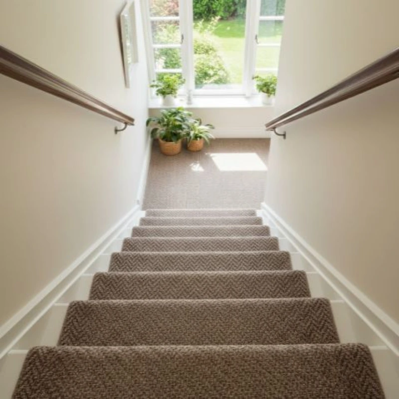 Brown textured herringbone carpet runner on indoor stairs viewed from above.