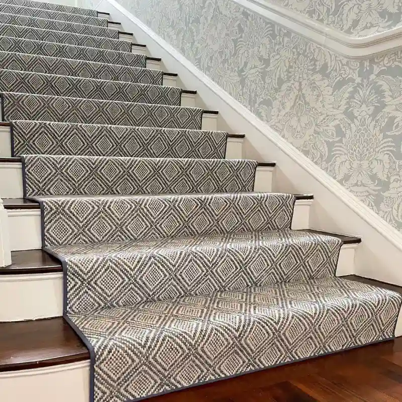 Diamond Pattern Stair Runner in grey and white on a dark wooden staircase with blue patterned wallpaper
