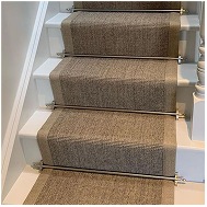 Natural sisal stair runner with textured beige fibers and brass stair rods.