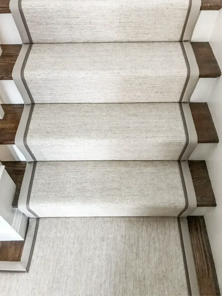 Neutral beige waterfall style stair carpet runner with clean border binding installed on wooden steps for Stair Carpet Runners Dubai.