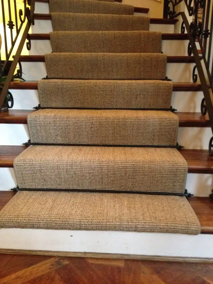 Textured natural coir stair carpet runner secured with dark metal stair rods for Coir Stair Runners Dubai.